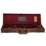 A BRASS-CORNERED LEATHER SINGLE GUNCASE, fitted for 30in. barrels, the interior lined with red