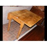 An antique pine drop leaf table on turned supports