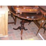 An antique tripod table with pie crust top