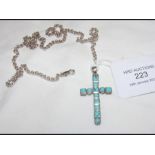 A turquoise and silver cross on chain