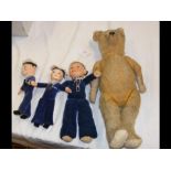 An antique straw-filled teddy bear, together with two Empire cloth sailor dolls and one other cloth