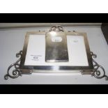 A silver elaborate photo frame together with a sil