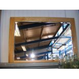 A bevelled wall mirror in light pine frame