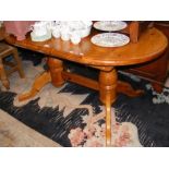 A pine oval dining table on twin pedestal supports