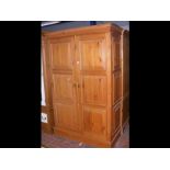 A pine wardrobe enclosed by a pair of panelled doo