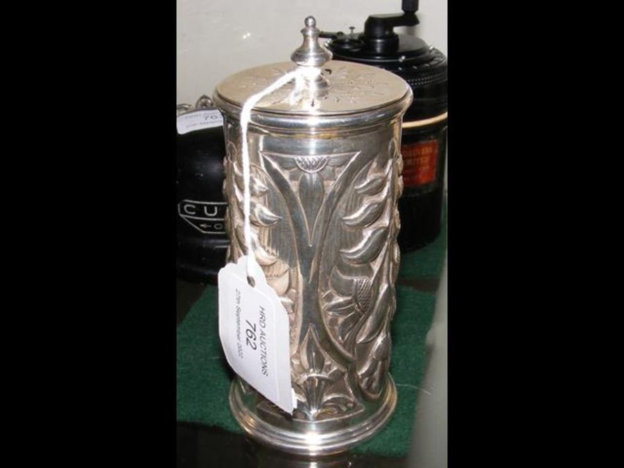 An embossed silver cylindrical pot with perforated