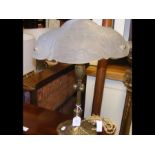 An ornate table lamp with cast metal base and glas