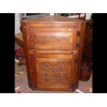 An oak corner cupboard with carved doors