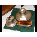 A silver capstan inkwell, another inkwell and a sn