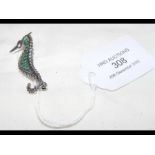 A silver seahorse set with emeralds