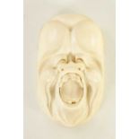 A JAPANESE MEIJI PERIOD CARVED IVORY GROTESQUE FACE MARK