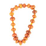 AN USUALLY LARGE AND SMALLER INTERMITENT STRING OF AMBER BEADS