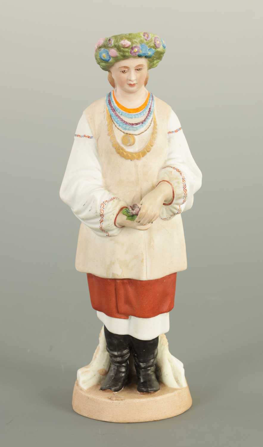 AN EARLY 20TH CENTURY RUSSIAN STANDING BISQUE FIGURE OF A FLOWER GIRL