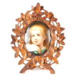 A LATE 19TH CENTURY GERMAN PORCELAIN PLAQUE IN CARVED BLACK FOREST FRAME