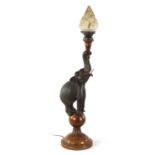 A STYLISH EARLY 20TH CENTURY AESTHETIC CARVED WALNUT AND EBONISED TABLE LAMP MODELLED AS AN ELEPHANT