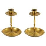 A PAIR OF ARTS AND CRAFTS PLANISHED BRASS CANDLESTICKS