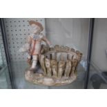 A Royal Worcester basket modelled as a young boy in sailor style costume seated beside a rustic.