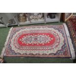 20thC Red ground medallion rug with tassel ends