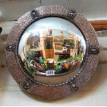 A convex mirror with wreath design beaten silver coloured frame