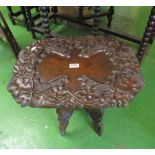 An Indian carved table on folding base