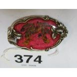 An enamel and red flower brooch set in silver-plate