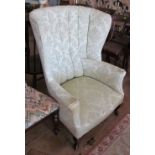 An antique wing armchair on cabriole legs with cream pattered fluted upholstered back