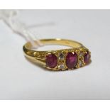A three stone ruby ring and four small diamonds on 18ct gold band 3.3gm, size K/L