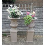 A pair of plastic campana planters on stands