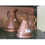 A set of three graduated copper jugs