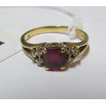 A gold coloured ring set red stone marked 750