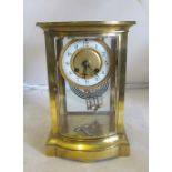 A 19th Century brass mantel clock with mercurial pendulum, bowed front door