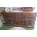 A large oak sideboard two drawers and four panelled cupboards with carved detail