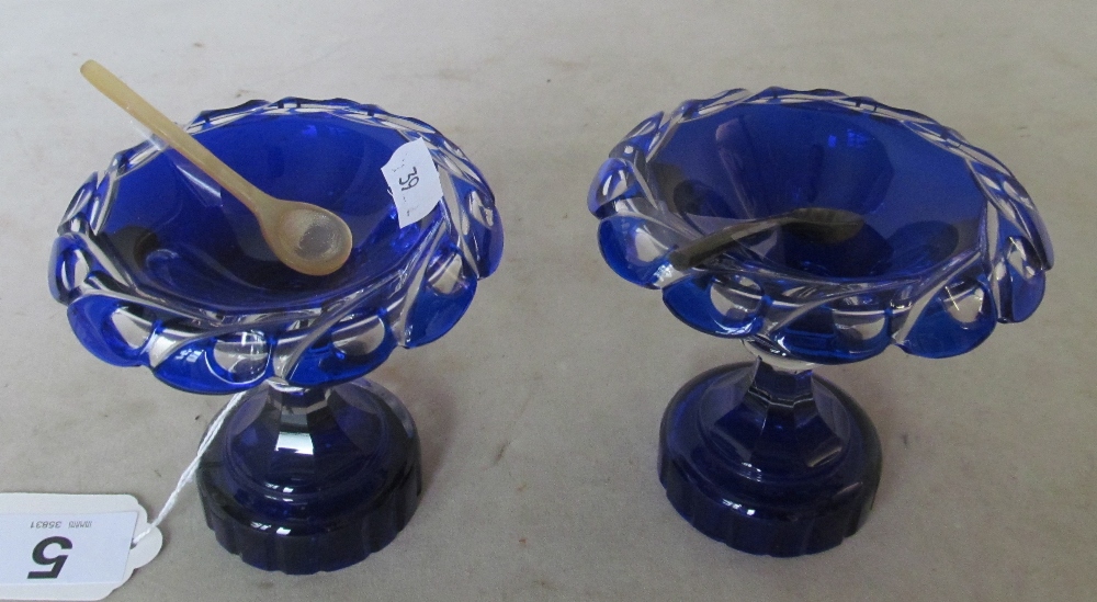 A pair of blue glass pedestal salts and spoons