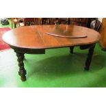 A large oak dining table with two leaves on barleytwist supports