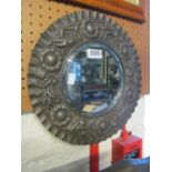 A copper framed circular mirror with beaten daisy pattern