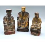 A Group Of Three Chinese Carved Hardwood And Gilded Seated Figures 22, 21 and 19 cms tall