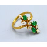An 18ct Gold Emerald And Diamond Ring set with three emeralds and seven diamonds of crossover