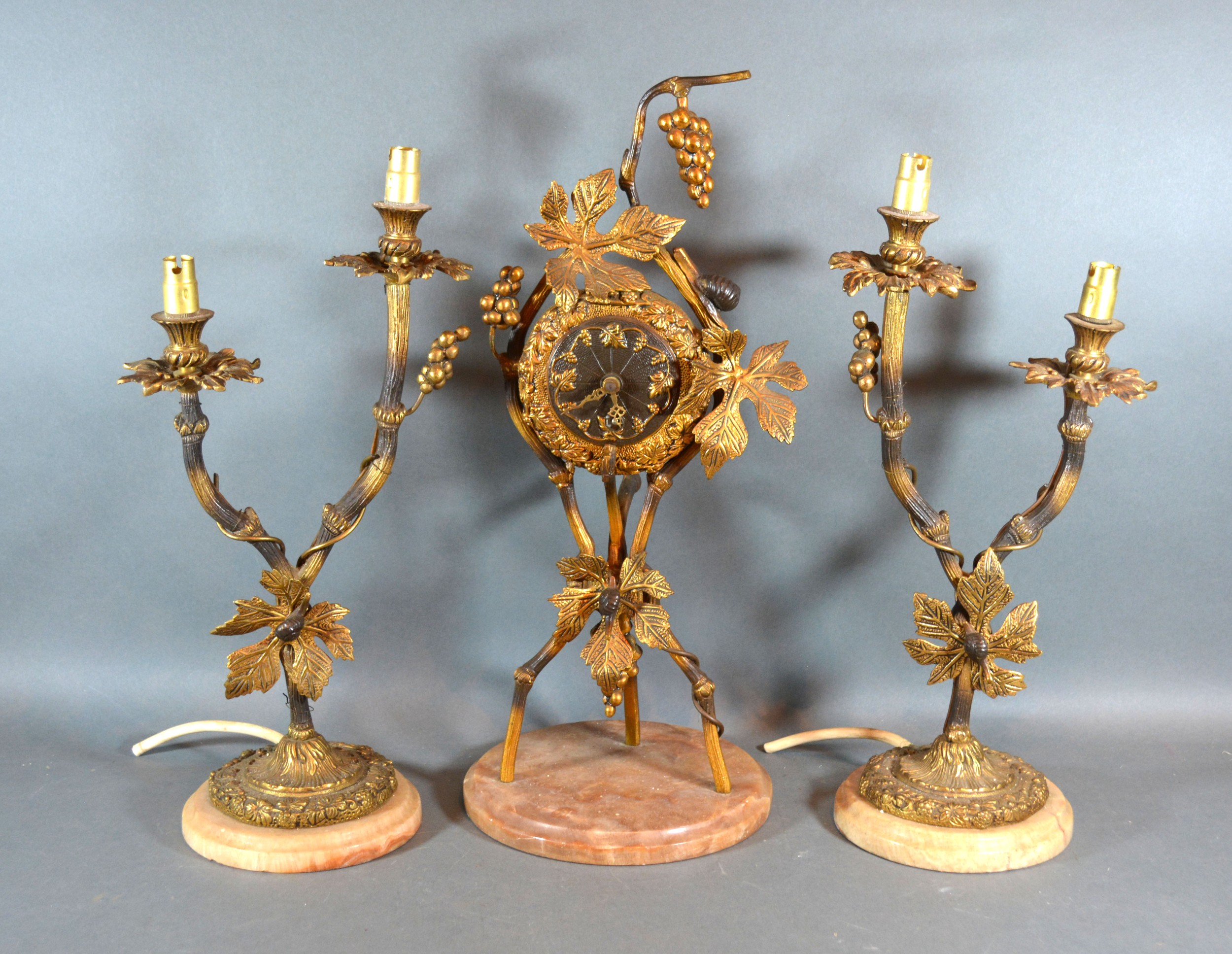 A French Three Piece Clock Garniture, the clock of grape vine form flanked by two branch