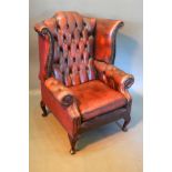 A Red Burgundy Leather And Button Upholstered Wingback Armchair with cabriole legs