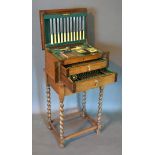 A Silver Plated Canteen Of Cutlery retailed by Walker & Hall within an oak cabinet, the hinged top