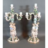 A Pair Of Dresden Porcelain Three Branch Candelabrum each with a figural column with putti amongst
