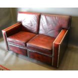 A Burgundy Leather And Brass Studded Three Piece Suite comprising a three seater sofa, a matching