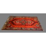 A North West Persian Woollen Rug with a central medallion upon an all over design with red, blue and