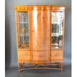 An Edwardian Sheraton Revival Satinwood Display Cabinet with a central serpentine door flanked by