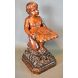 A Carved Wooden figure in the form of Putti Holding A Cushion kneeling upon naturalistic base 67 cms