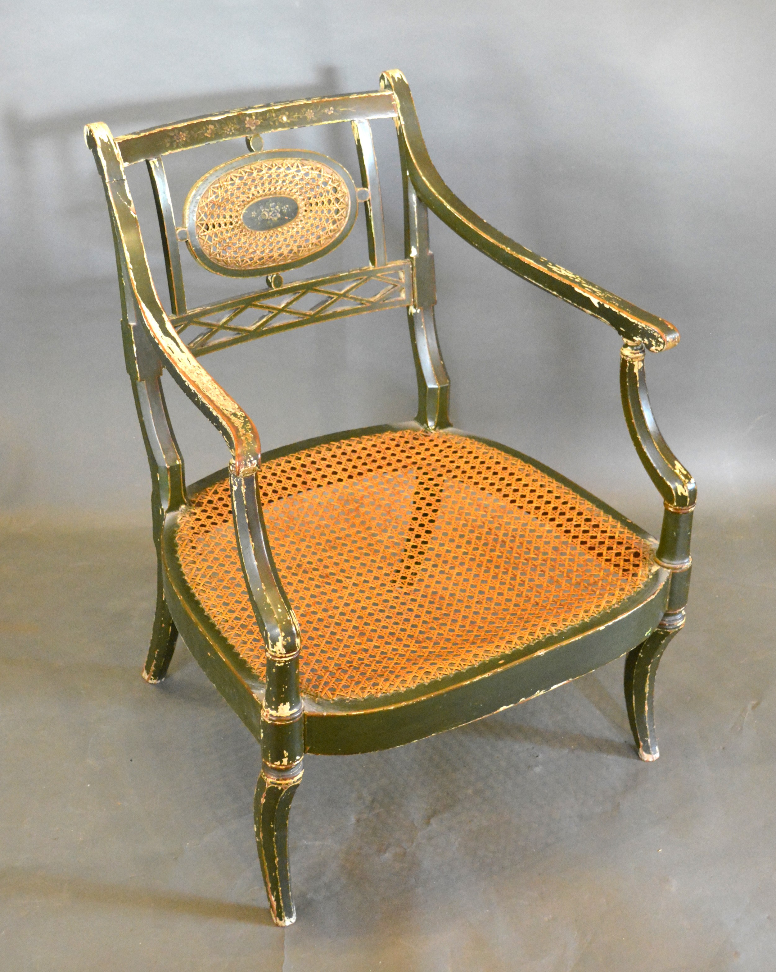 A Regency Painted Armchair, the oval cane and pierced splat back above a cane seat with shaped arms,
