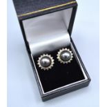 A Pair Of 18ct. Gold Diamond And Grey Pearl Set Ear Studs, each set with a grey pearl surrounded