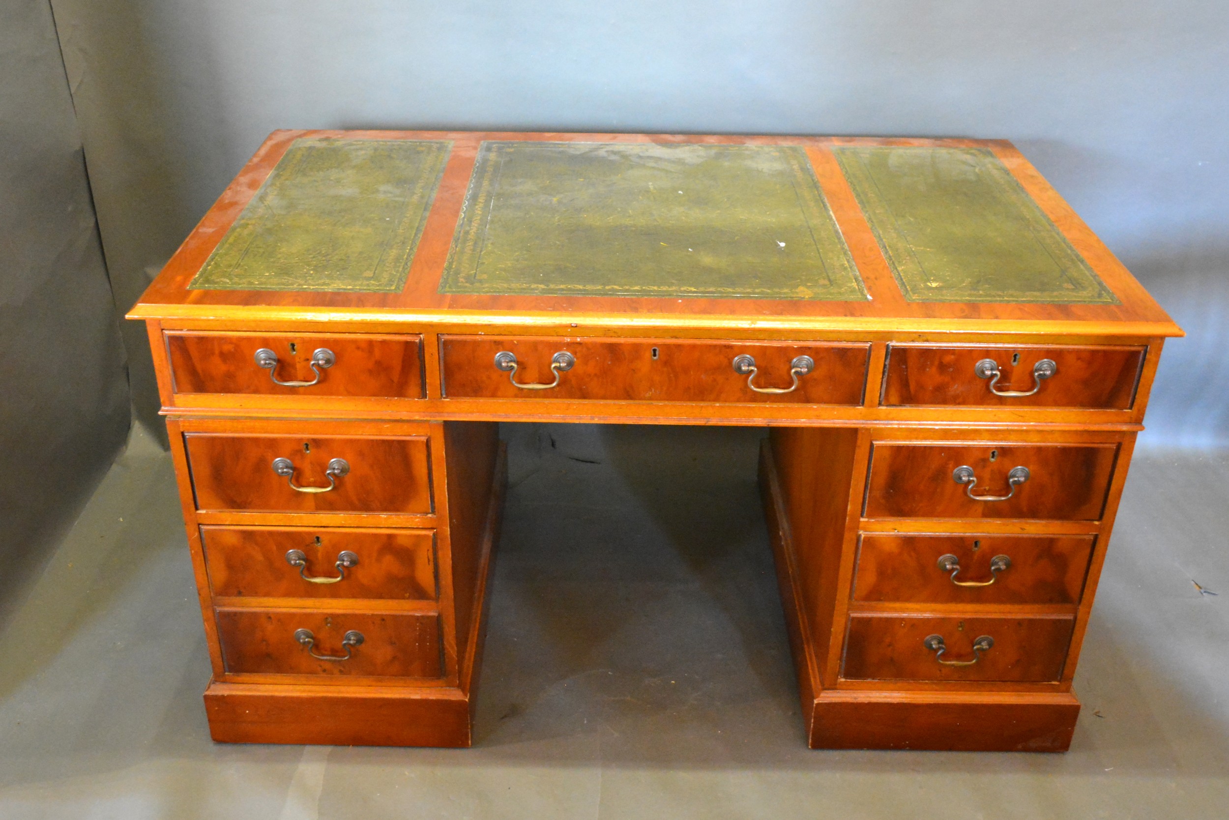 A Twin Pedestal Desk, the tooled leather inset top above nine drawers with brass handles, raised