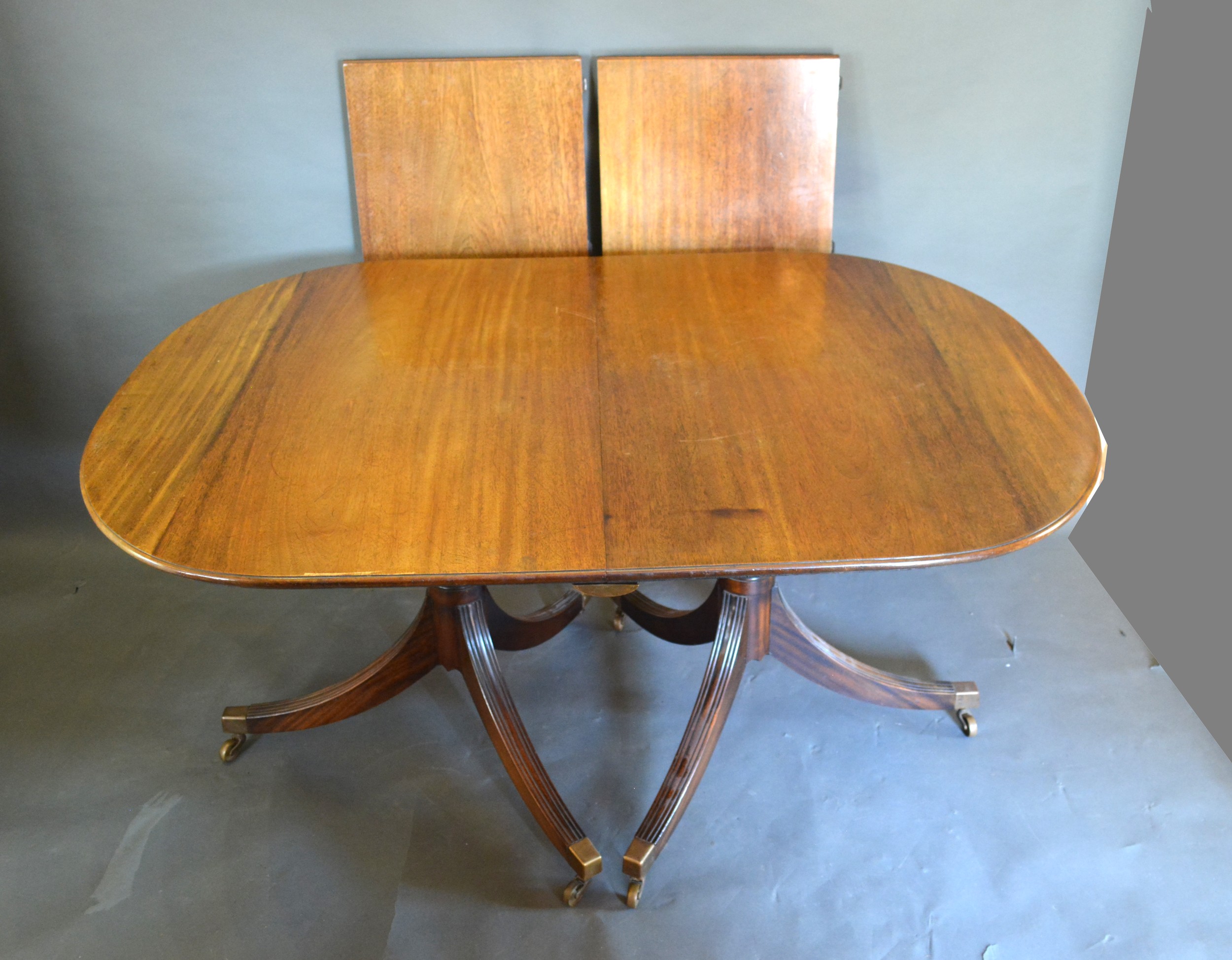 A Regency Style Mahogany Extending Dining Table, the moulded top above twin end supports with reeded