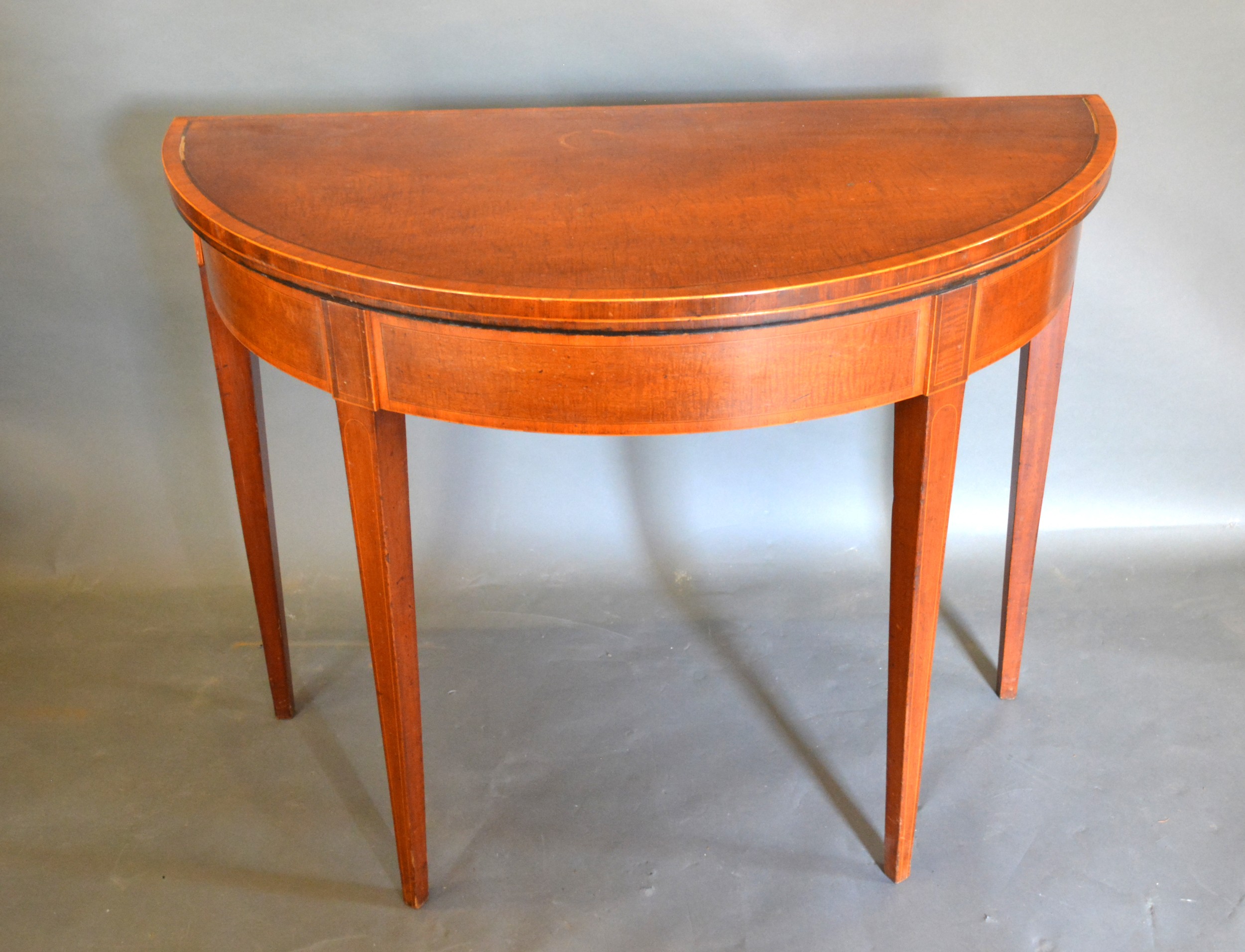 A 19th Century Mahogany Satinwood Crossbanded Demi Lune Card Table with square tapering legs